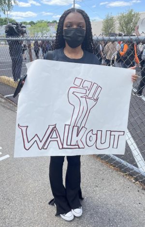 Sophomore Jenelle Dupre demonstrates the handmade poster she created the protest.