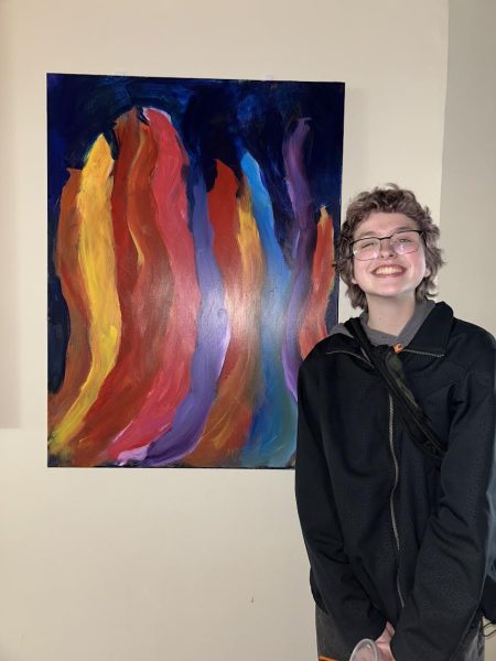 Senior Ace Donnelly posed next to his colorful flame painting he did in his Intermediate Painting class.