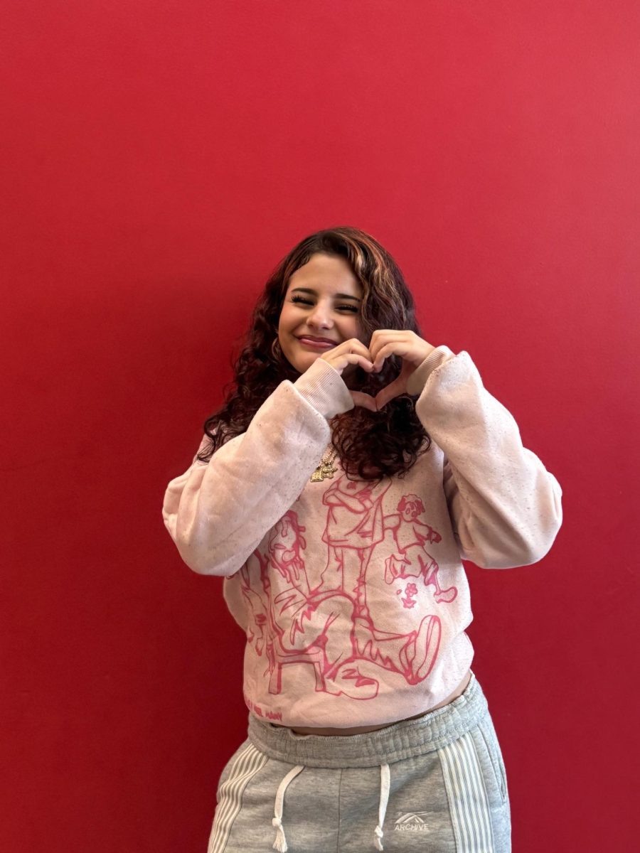 Freshman Ashley Santos, posing in front of the red wall. 