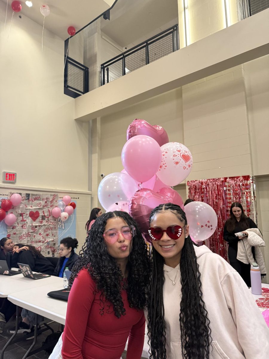 Seniors Suelly Pais and Leosmary Perez are dressed in festive Valentine's gear at the photo booth. 