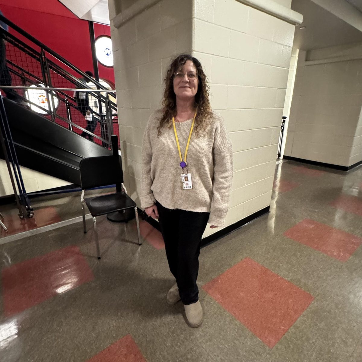 Success coach Michelle Farina Wearing a beige knit sweater, black pants, lights beige UGG mini boots, glasses, and her id.