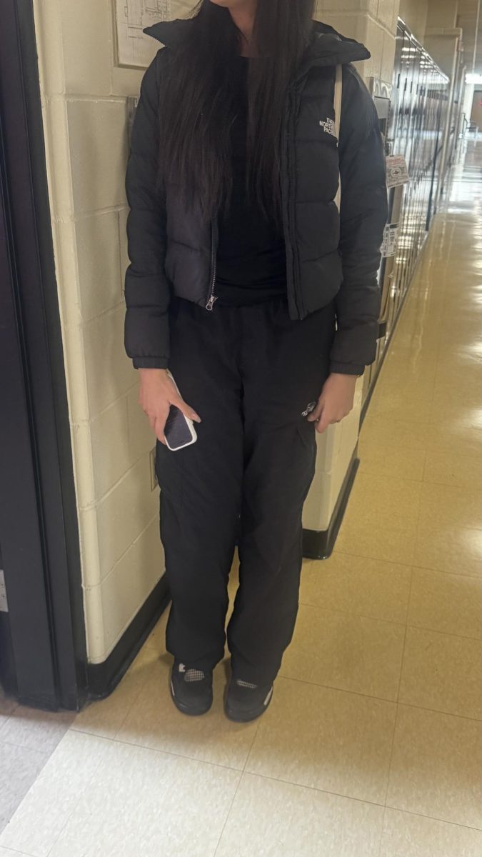 Junior Isabelle de Oliveira is looking good in a North Face puffer jacket, black pants, and black Jordan 4 shoes.