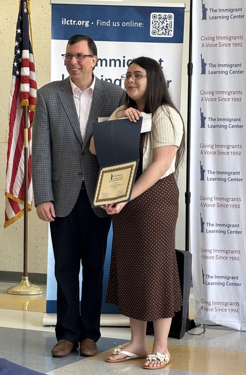 First place art award winner Carolina Rivas receives her award certificate with Immigrant Learning Center director Vince Rivers