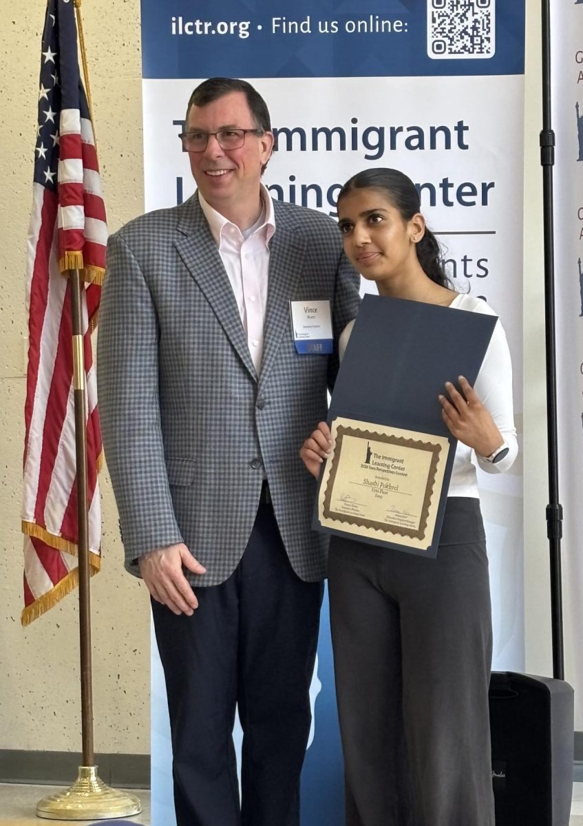 First place essay winner Shashi Pokhrel receives her award certificate with Immigrant Learning Center director Vince Rivers.